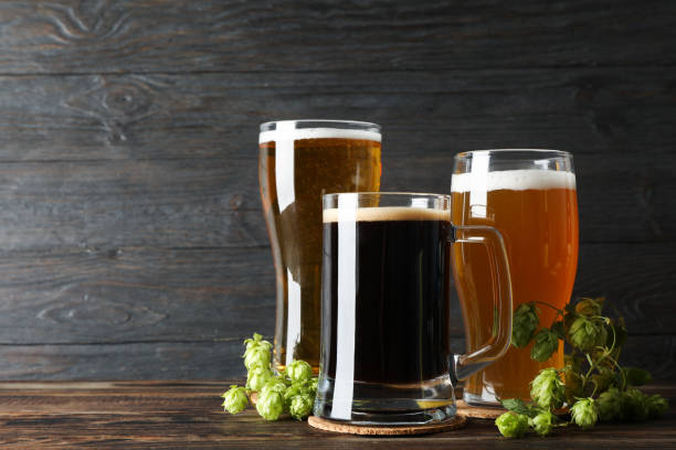 istock Different mugs with beer and hop cones on wooden table, copy space 1174947821