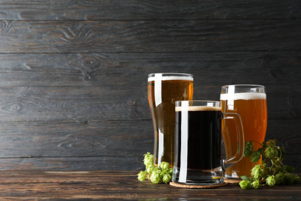 istock Different mugs with beer and hop cones on wooden table, copy space 1174947901