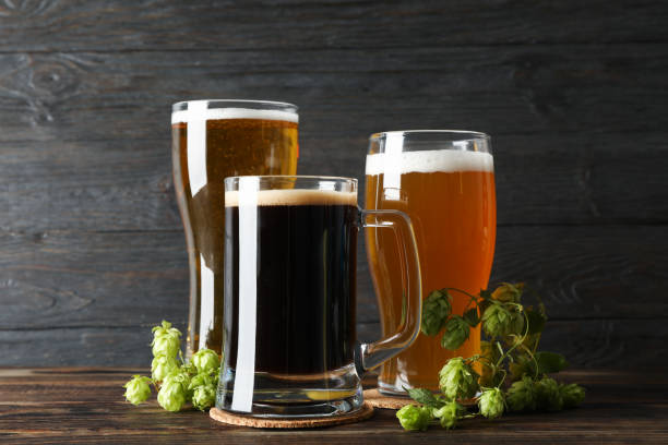 istock Different mugs with beer and hop cones on wooden table, copy space 1174947955