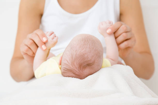 mãos novas da matriz que prendem suas mãos pequenas infantis. brincando com o bebê. momento adorável e emocional. conceito do relacionamento. closeup. - newborn little girls baby lying down - fotografias e filmes do acervo