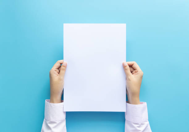 istock close up hands holding  empty white blank letter paper size A4 for flyer or invitation mock up isolated on a blue background. 1174948327