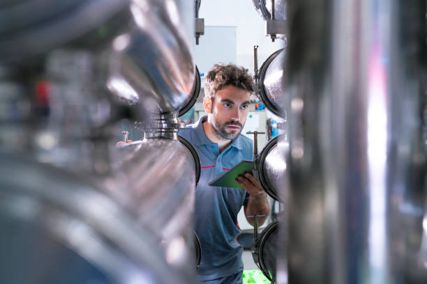 Young worker in winery quality control Young worker in winery with cooling stainless steel quality control tablet PC high quality technology stock pictures, royalty-free photos & images