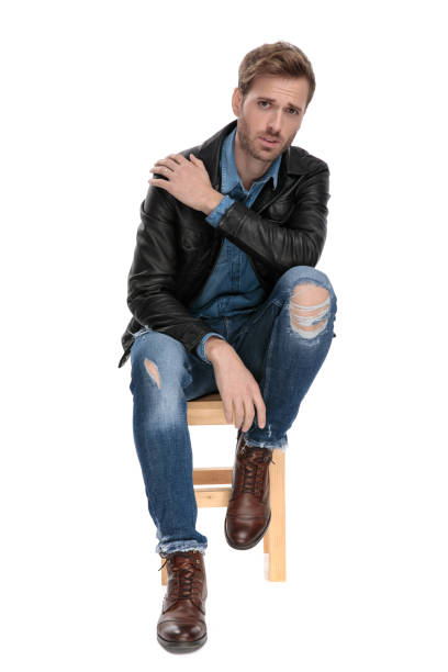 istock man sitting and holding his shoulder 1174951891