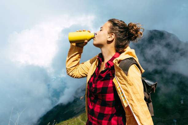 istock woman in the mountains drinks water from a bottle 1174952795