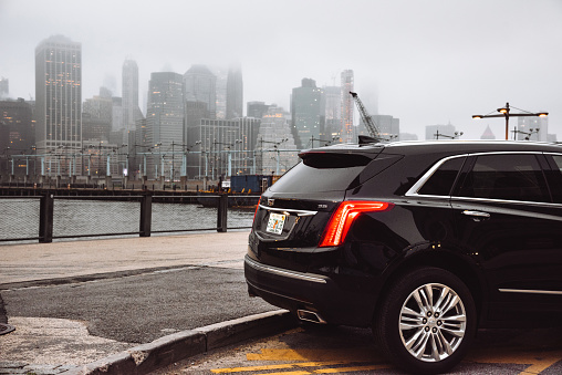 Brooklyn, New York, USA - May 3, 2019: Rear view of a 2018 Cadillac XT5 parked in Brooklyn Heights in the city of New York City . XT5 is the new suv by Cadillac, one of the most famous automotive brand in United States. Foggy day with the Manhattan skyline in the background.