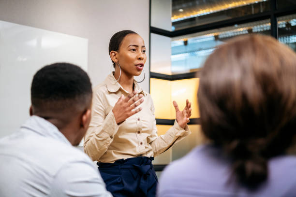 młoda bizneswoman wyjaśniająca i gestykulująca na spotkaniu - female business confidence meeting zdjęcia i obrazy z banku zdjęć