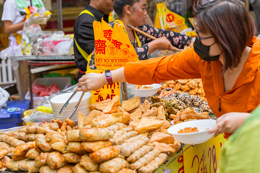 People buying vegan food sale only during Vegetarian Festival (J Festival) In Thailand at Yaowarat or Bangkok China town street decoration with yellow flag for No animal meat food sign. 10 October 2018. Bangkok, THAILAND.
