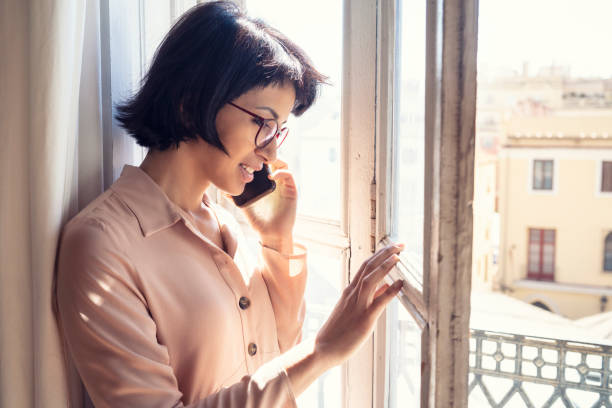 istock Brunette talking with mobile phone in sunny window 1174960720