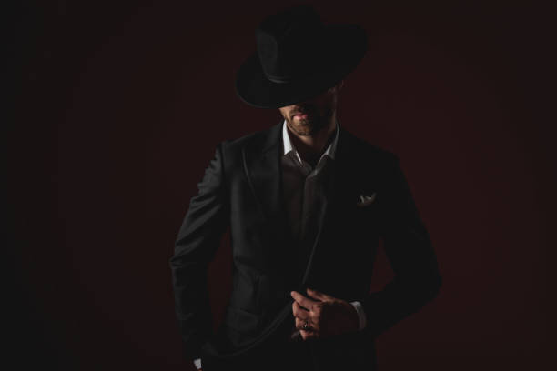 istock confident young man fixing his coat and looking down 1174965200