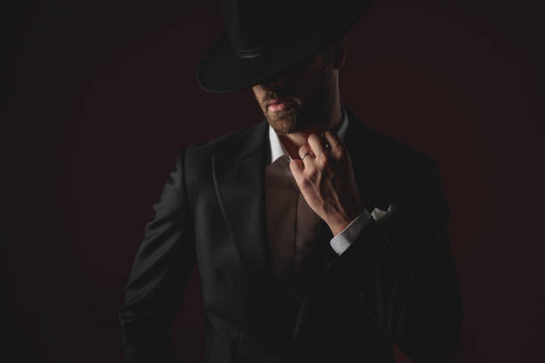 istock mysterious young man fixing collar on black background 1174965774