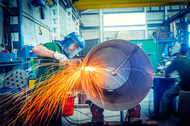 Industry worker cutting metal tank with a grinder jumping sparks