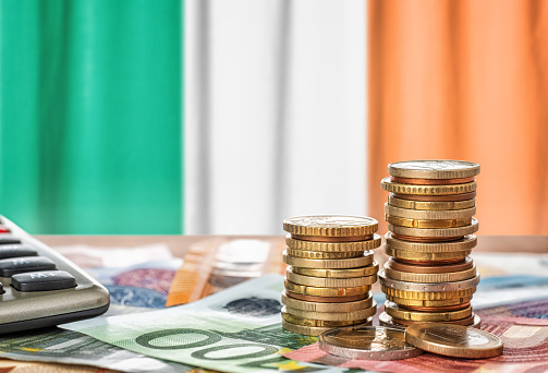 Billetes y monedas en euros frente a la bandera nacional de Irlanda photo