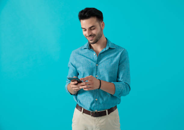 istock man in blue shirt standing while looking at his phone 1174972745
