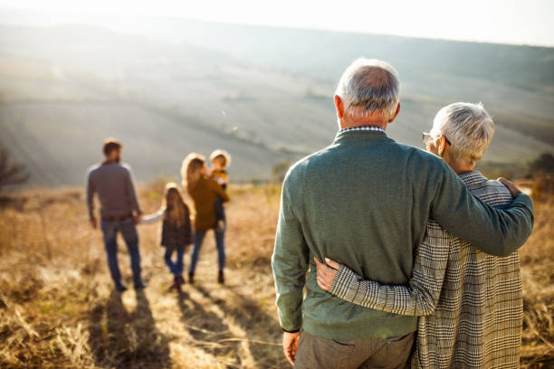 自然の中で家族を見ている抱擁された先輩夫婦の背面図。 - 丘 写真 ストックフォトと画像