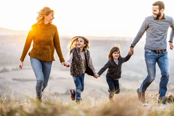 istock Happy family having fun while holding hands and running in autumn at sunset. 1174973038