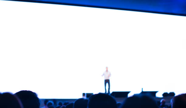 istock Seminar presenter at conference giving speech. Speaker giving lecture to business audience. Defocused lecturers leading discussion at business training event background. 1174973723