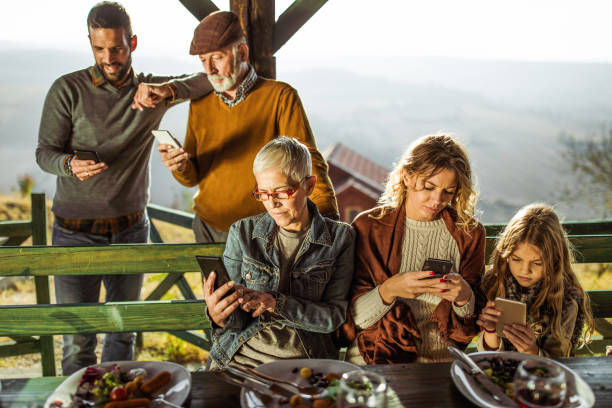 istock Extended family using mobile phones during their meal on a terrace. 1174974125