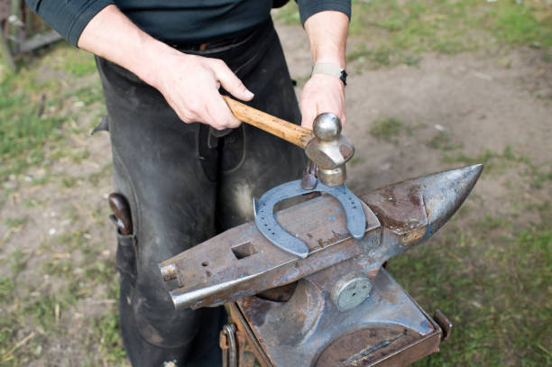 istock Blacksmith forges horseshoe with hammer on anvil. Ancient craft. Village craft. Blacksmith working metal. Tools for craft in workshop. Blacksmith occupation concept 1174974761