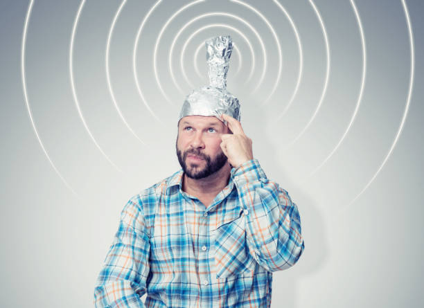 Bearded funny man in a cap of aluminum foil sends signals. Concept art phobias Bearded funny man in a cap of aluminum foil sends signals. Concept art phobias tin foil hat stock pictures, royalty-free photos & images