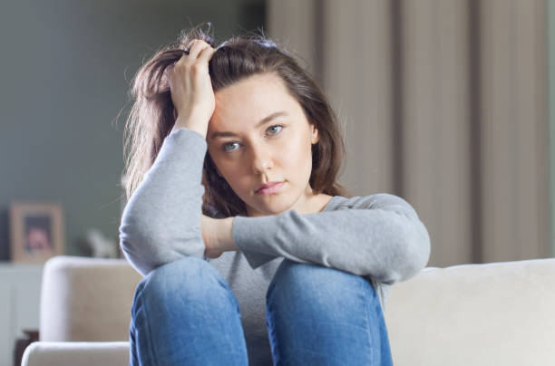 istock Depressed young woman on sofa at home 1174977095