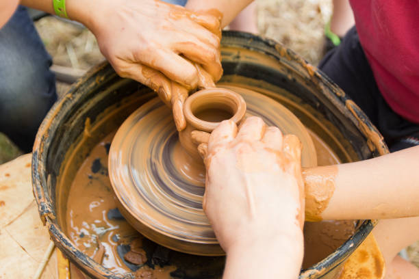 istock A close up view on ceramic production process on potter's wheel with children. Clay crafts with kids concept. 1174978966