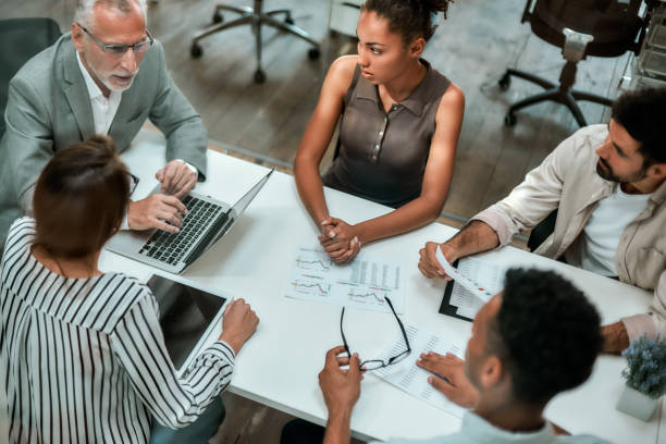 istock Top view of multicultural team discussing business while sitting at the office table together 1174978970