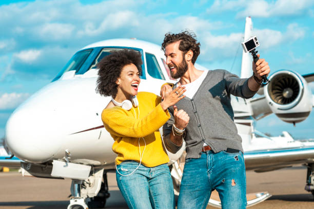 couples célèbres de vlogger faisant un spectacle ensemble à côté du cône de nez d'un avion privé garé sur une voie de taxi d'aéroport - status symbol audio photos et images de collection