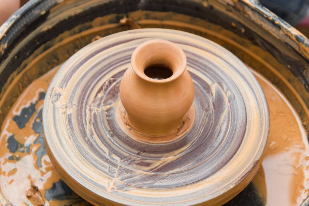 istock A close up view on ceramic production process on potter's wheel with children. Clay crafts with kids concept. 1174981474