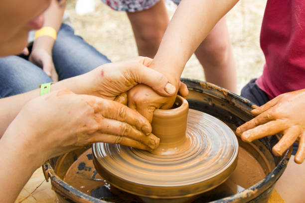 istock A close up view on ceramic production process on potter's wheel with children. Clay crafts with kids concept. 1174983269