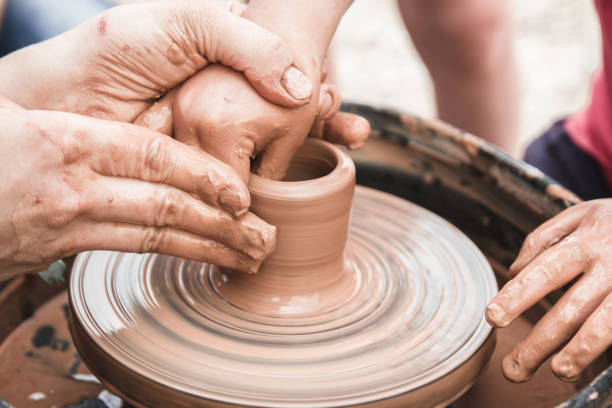 istock A close up view on ceramic production process on potter's wheel with children. Clay crafts with kids concept. 1174983528