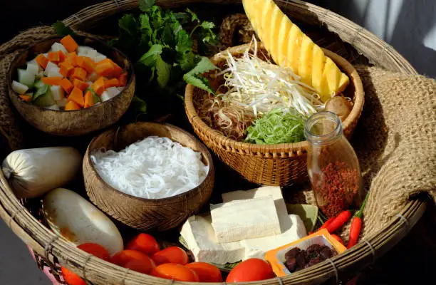 Prepare raw materials for vegan rieu noodle soup or vegetarian bun rieu, a traditional Vietnamese food with tomato, tofu, tamarind, pine apple, sausage, herbs, vegetable and rice vermicelli