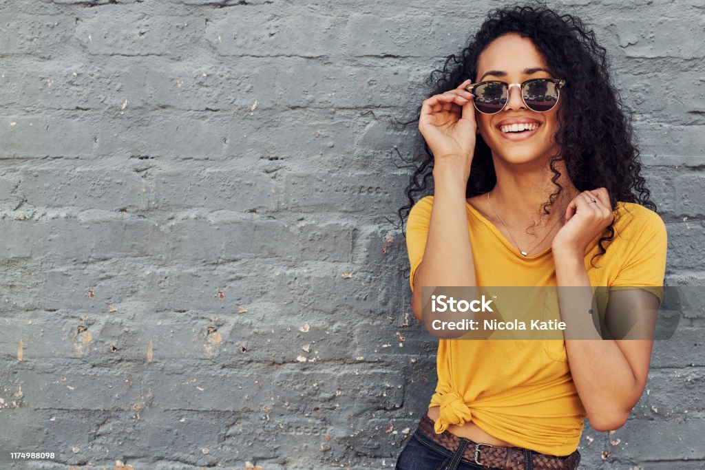 I am summer ready Cropped portrait of an attractive young woman wearing sunglasses and smiling while standing against a gray background outdoors Sunglasses Stock Photo