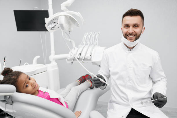 istock Cheerful male dentist smiling while working and curing teeth 1174990257