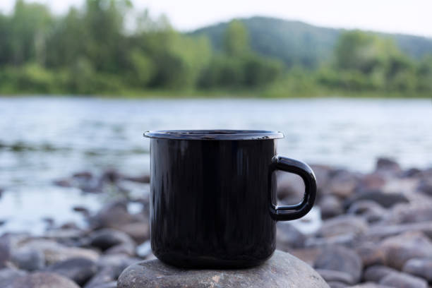 istock Black campfire mug mockup with stony river bank 1174993033