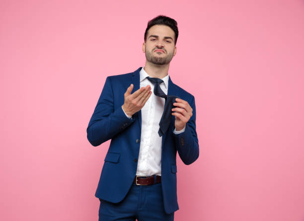istock smart casual man holding tie on pink background 1174993089