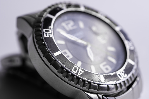 Diver watch case part closeup on white background. Bezel is black and scratched. Glass is cracked.