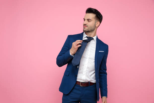 istock smart casual man holding tie on pink background 1174994713