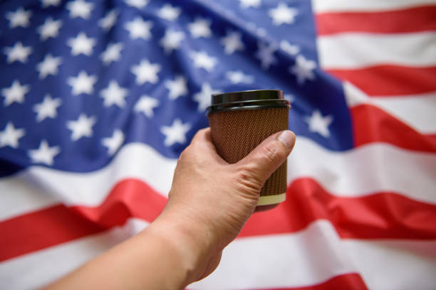 istock Man hand holding paper cup with American flag background 1174996071