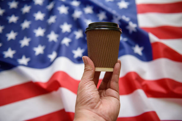 istock Man hand holding paper cup with American flag background 1174996360
