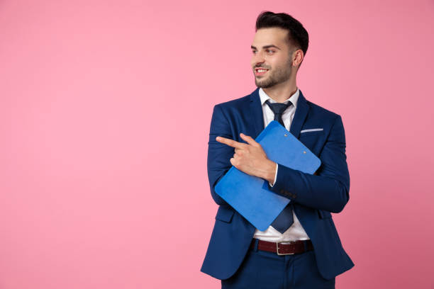 istock attractive young man holding clipboard and pointing finger 1174999095