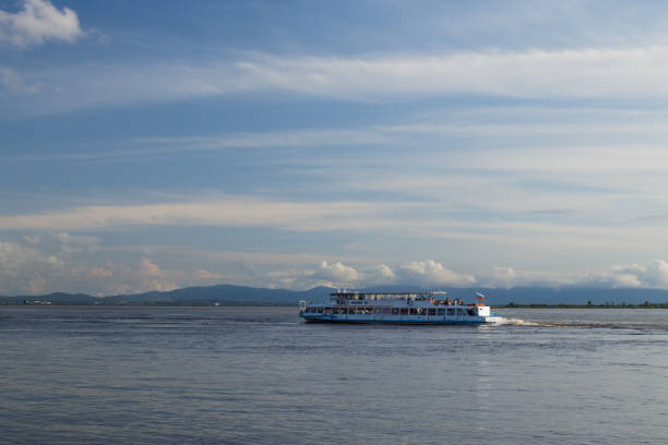 Khabarovsk, Russia - August 20, 2019. Walking excursion river ship with tourists moves along Amur River. Water level in river is higher than normal. Flooded shores are visible on opposite side.