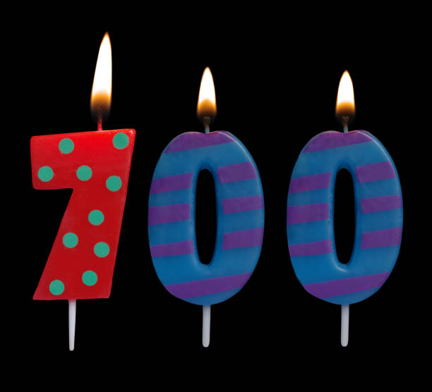 istock Burning birthday candle isolated on black, number 700 1175002871