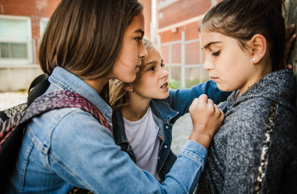 un triste momento de intimidación de chicas en la edad primaria bullying en schoolyard - acoso escolar fotografías e imágenes de stock