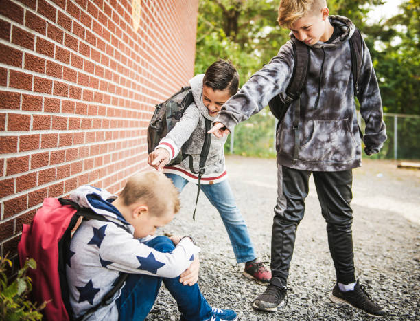 triste momento di intimidazione elementary age bullismo a schoolyard - bullying sneering rejection child foto e immagini stock