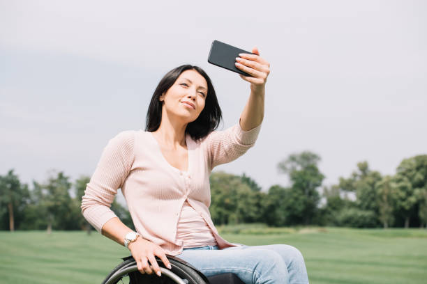 istock cheerful disabled woman taking selfie on smartphone while walking in park 1175005147