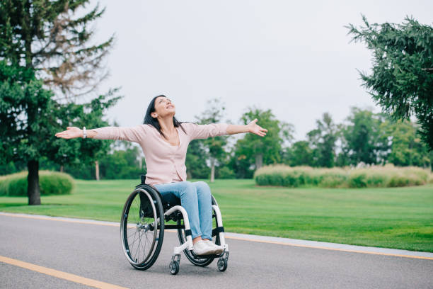 istock happy disabled woman in wheelchair gesturing while looking at clear sky 1175005269