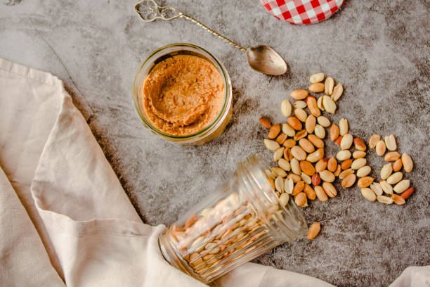 Creamy and smooth peanut butter in jar on gray table. Natural nutrition and organic food. Selective focus.Comfort food concept. stock photo