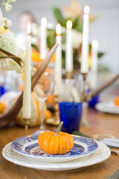 istock Luxurious elegant wedding decor in autumn style. Wooden vintage table setting with ceramic plates and silver cutlery. Fresh flowers in a vase, orange pumpkins, deer horns and candles. Romantic dinner. 1175007776