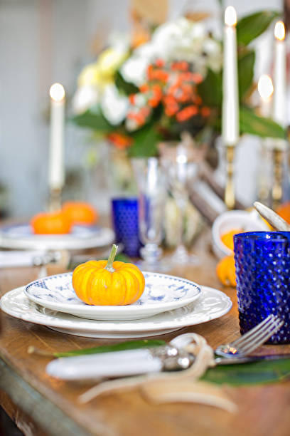 istock Luxurious elegant wedding decor in autumn style. Wooden vintage table setting with ceramic plates and silver cutlery. Fresh flowers in a vase, orange pumpkins, deer horns and candles. Romantic dinner. 1175007831