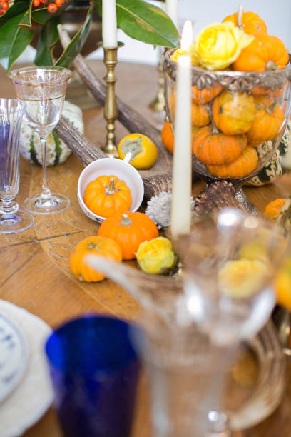 istock Luxurious elegant wedding decor in autumn style. Wooden vintage table setting with ceramic plates and silver cutlery. Fresh flowers in a vase, orange pumpkins, deer horns and candles. Romantic dinner. 1175008930